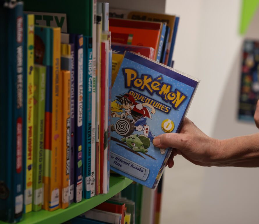 Library user lifting Pokemon Adventures Book off the shelves